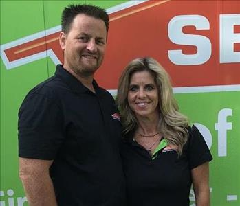 Male and female in front of green SERVPRO vehicle.